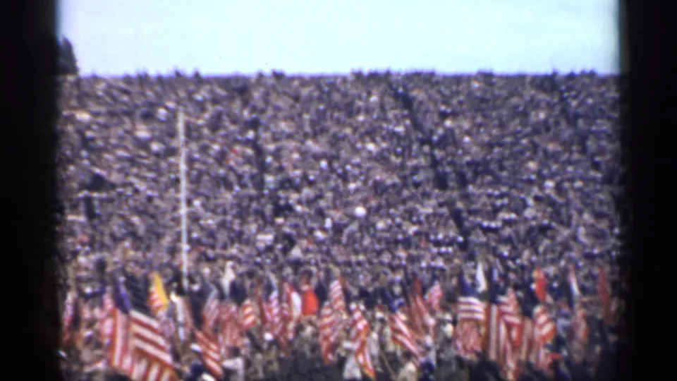 Color 8mm frame from 1944 showing a packed San Francisco stadium and clustered United States flags in front.
