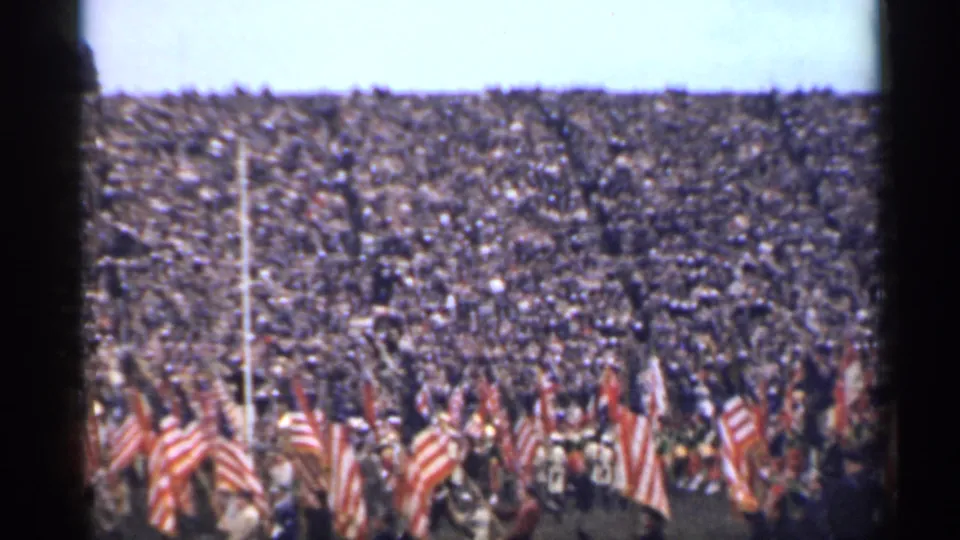 1944 San Francisco frame with a large stadium audience and multiple American flags visible in front of the stands.