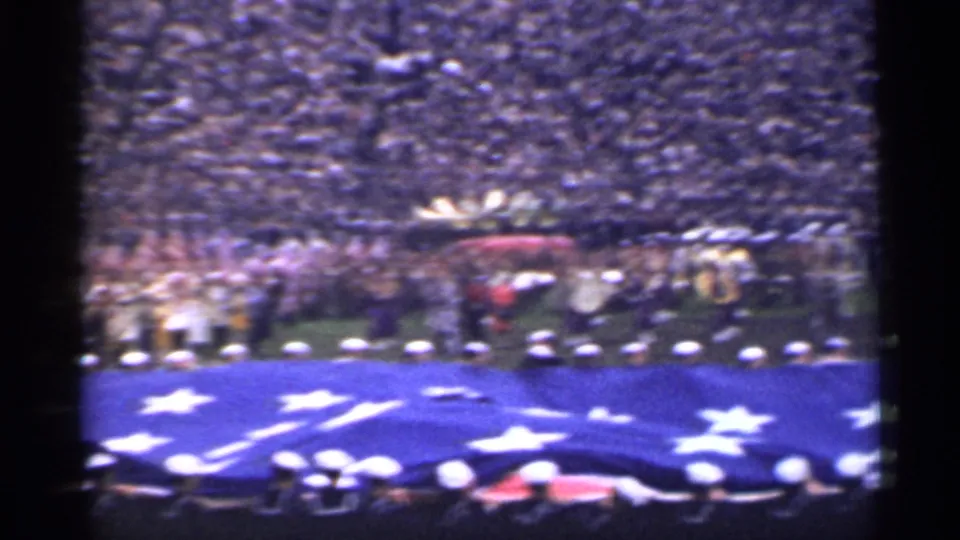 1944 San Francisco home-movie view of uniformed personnel holding a large American flag on a stadium field before crowded stands.