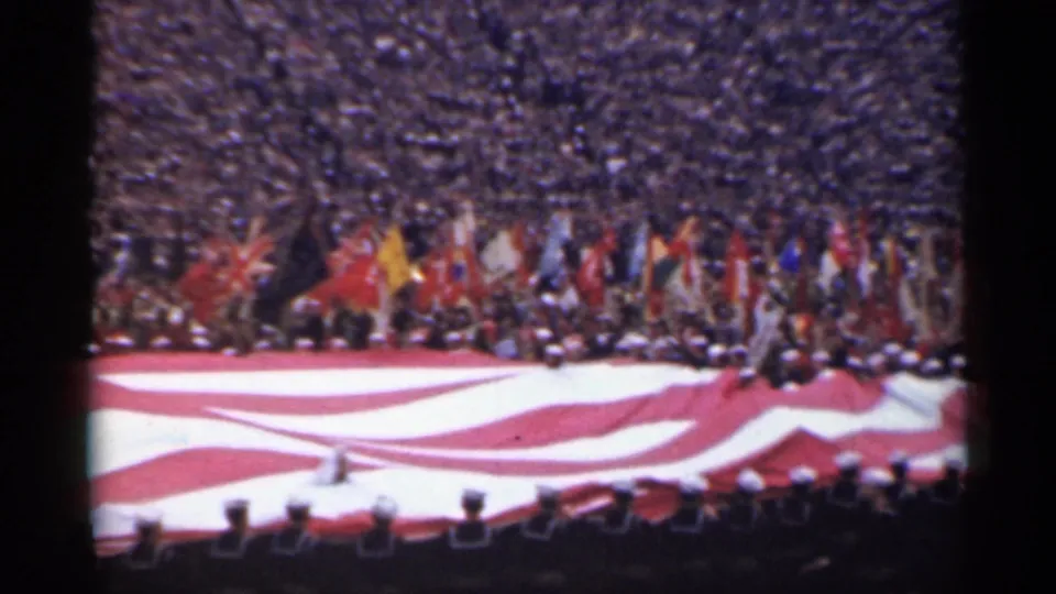 Flag bearers and uniformed personnel gather along the far side of the field during the San Francisco stadium ceremony.
