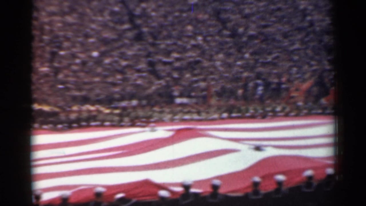 1944 San Francisco home-movie frame with a huge American flag stretched across a stadium field before spectators.