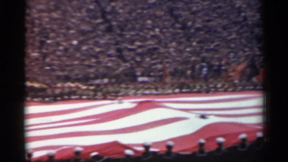 1944 San Francisco home-movie frame with a huge American flag stretched across a stadium field before spectators.