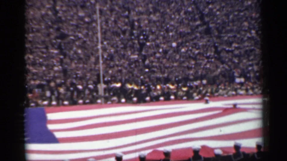 1944 San Francisco 8mm view of a stadium crowd watching a large American flag ceremony on the field.