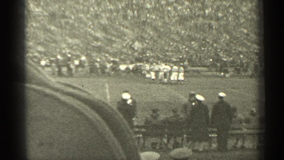 1944 San Francisco stadium view with football players in the distance, a curved walkway, and men in caps watching from the sideline.