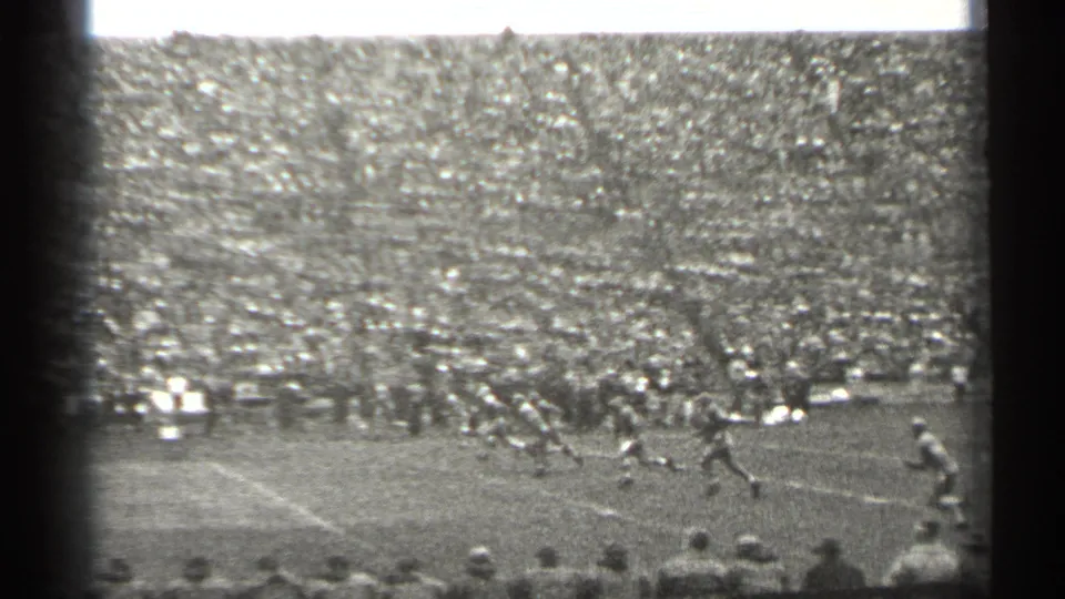 Wide 1944 San Francisco stadium frame showing football action on the field and a large crowd filling the bleachers.