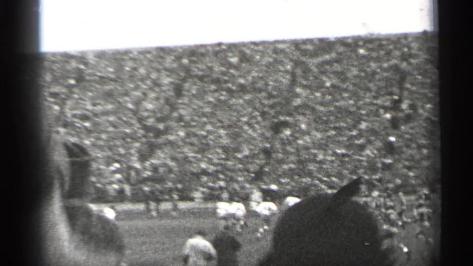 A crowded San Francisco stadium in 1944, with football players visible on the field and a spectator partly blocking the home-movie view.