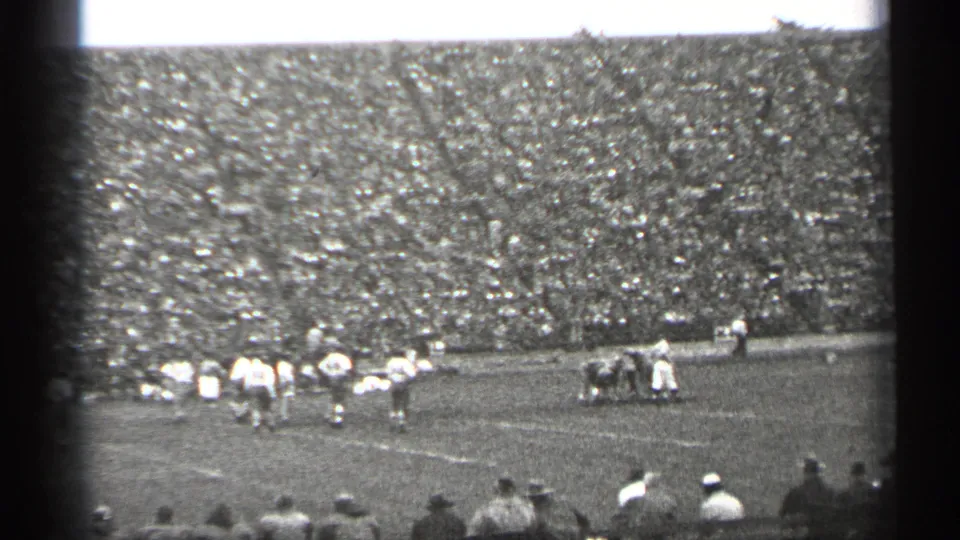1944 San Francisco footage frame with players spread across the field and a packed stadium crowd in the background.