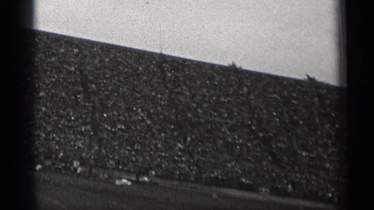 Packed stadium stands seen from a low angle with the football field along the bottom edge.