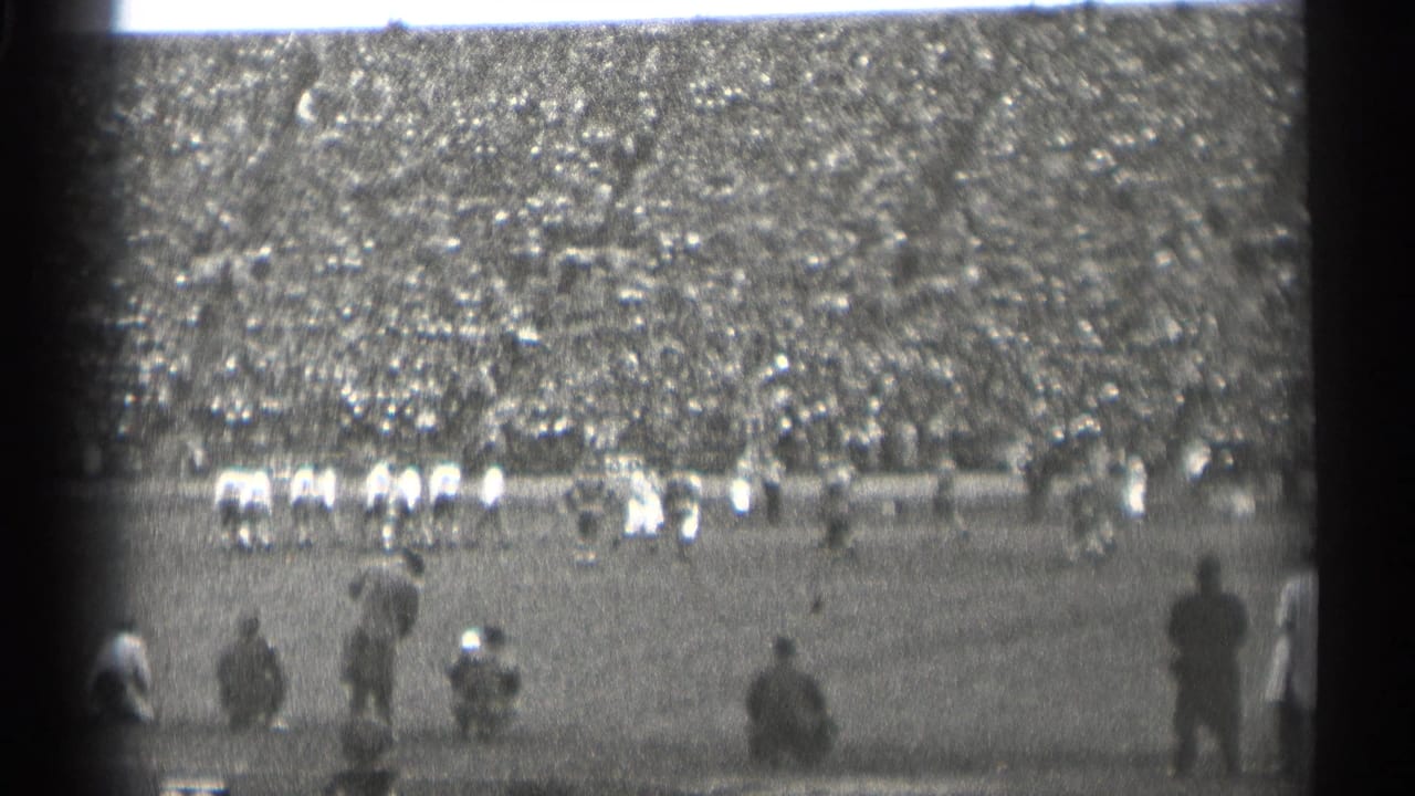 A 1944 San Francisco football game appears in soft focus, with players on the field and a large crowd behind them.