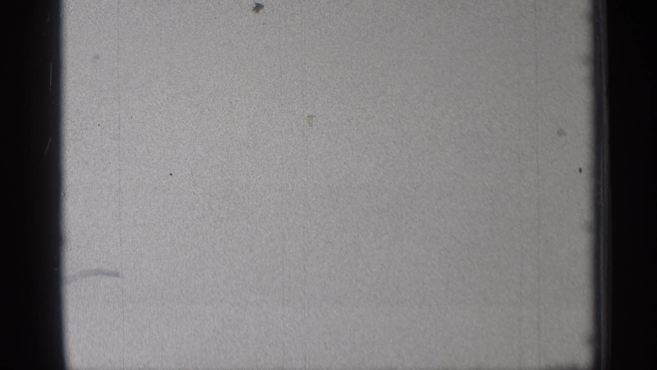 Blank or overexposed film leader with dust marks and dark frame edges.