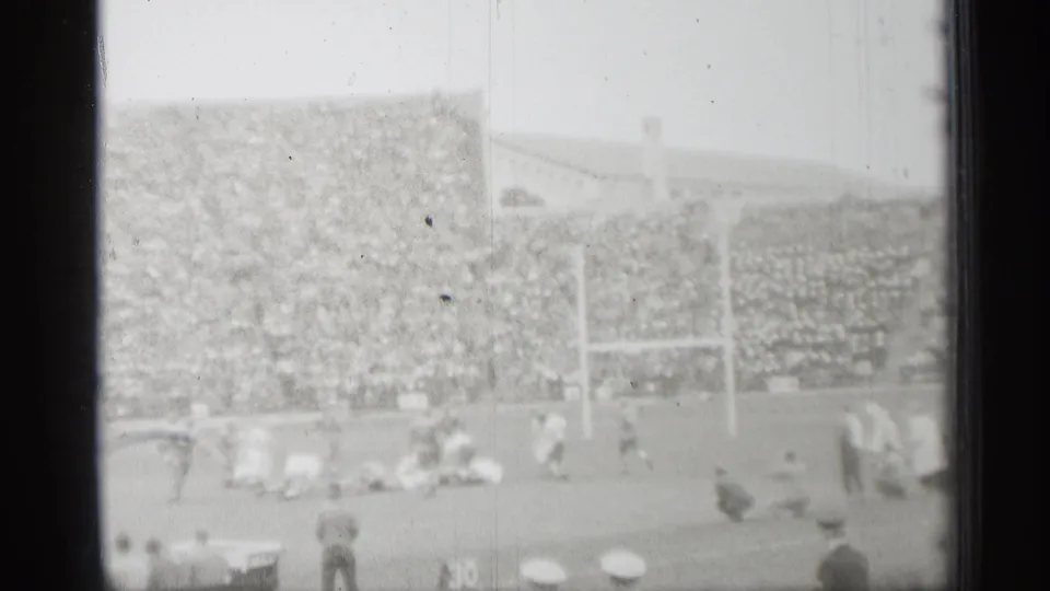 1944 San Francisco home-movie view of a football field, packed stands, goal posts, and sideline figures seen from a spectator position.