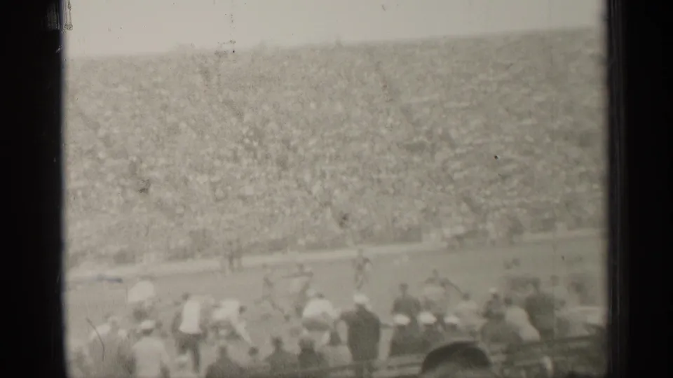 1944 San Francisco 8mm footage shows a distant football play before packed stadium stands and foreground spectators.