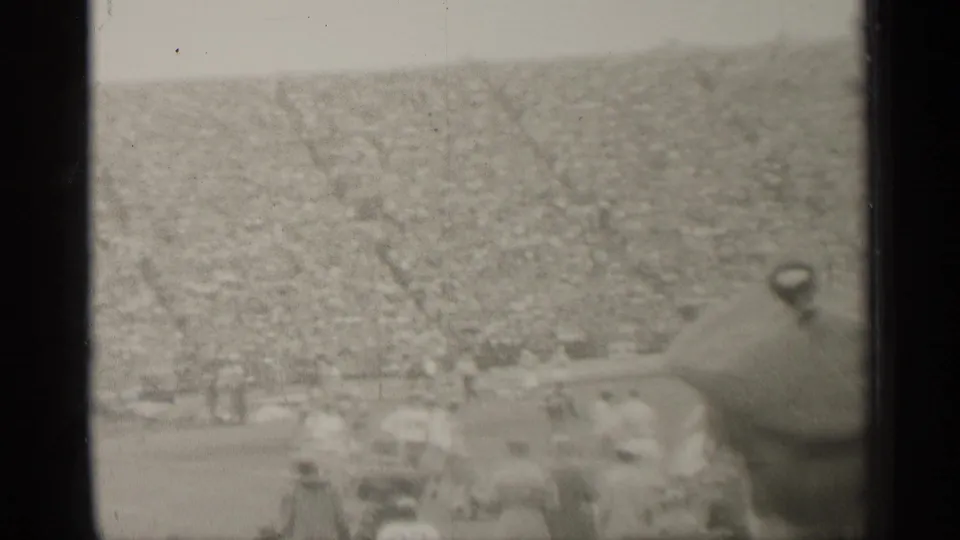 A soft 1944 San Francisco stadium view shows football players and a dense crowd from a spectator position.