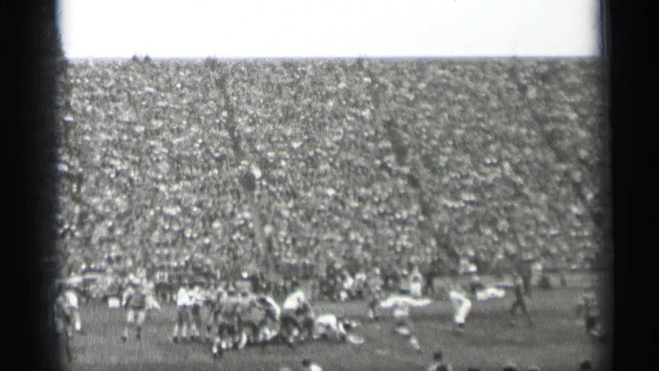 1944 San Francisco football game viewed from the stands, with players clustered on the field and a dense crowd behind them.