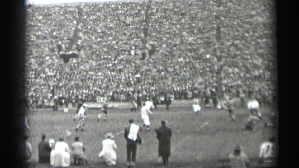 1944 San Francisco football game viewed from the sideline, with players on the field and packed bleachers beyond.