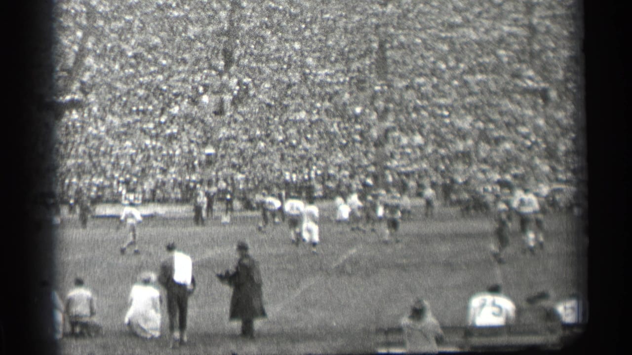 A spectator viewpoint of a 1944 San Francisco football game, showing field action, sideline viewers, and a dense stadium crowd.