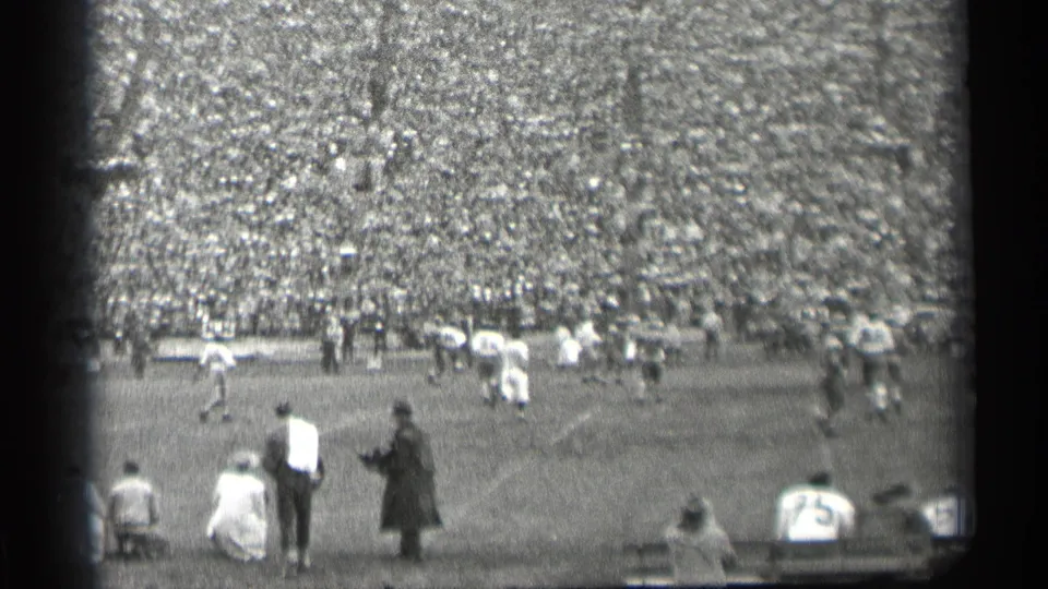 A spectator viewpoint of a 1944 San Francisco football game, showing field action, sideline viewers, and a dense stadium crowd.