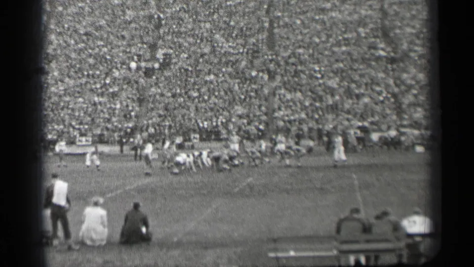 1944 San Francisco football teams appear to line up for a play, with spectators seated along the sideline and a packed crowd behind them.