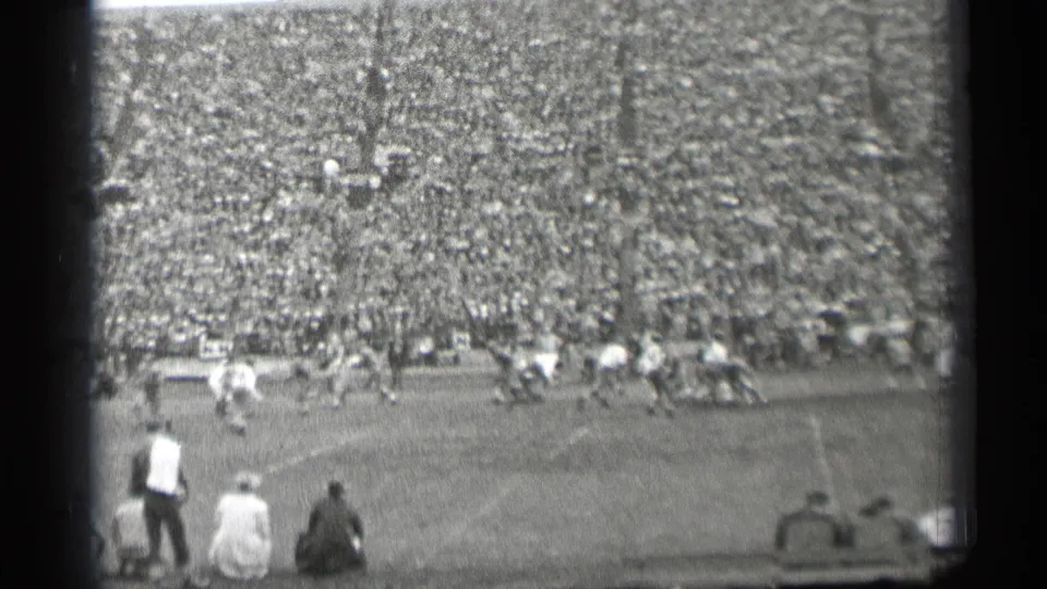 A wide 1944 San Francisco stadium view shows football players in motion, sideline observers, and a full grandstand.