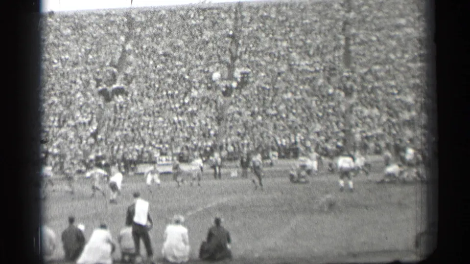 1944 San Francisco football game from a high spectator viewpoint, with players on the field, seated foreground viewers, and crowded stands.