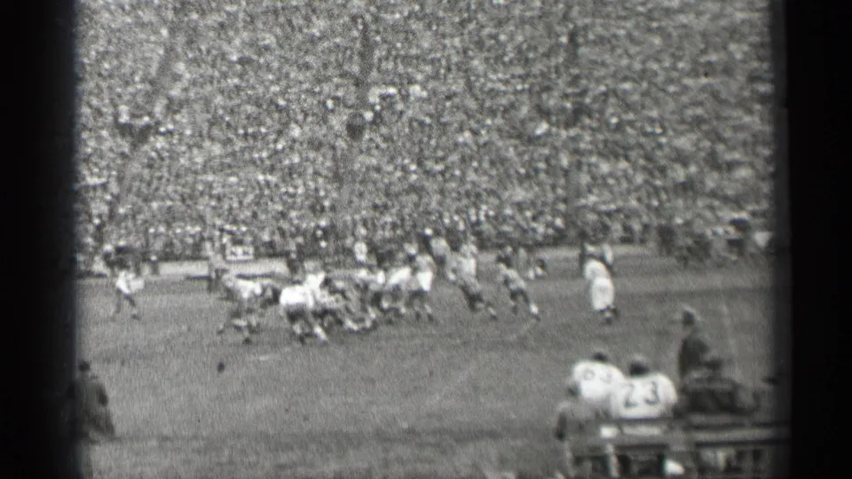 1944 San Francisco stadium view with a football tackle or pile-up near the center of the field and spectators filling the background.