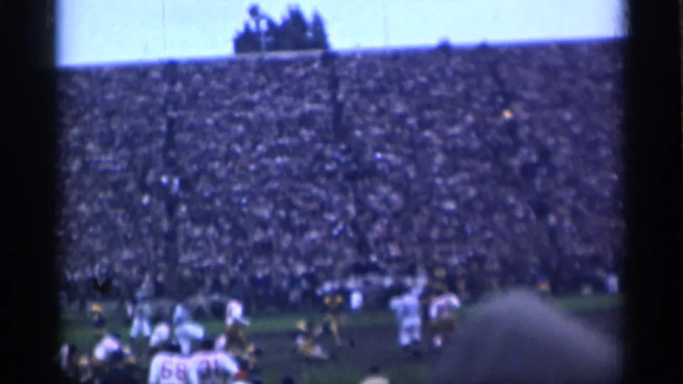 1944 San Francisco football game viewed from the stands, with players on the field and a packed crowd behind them.