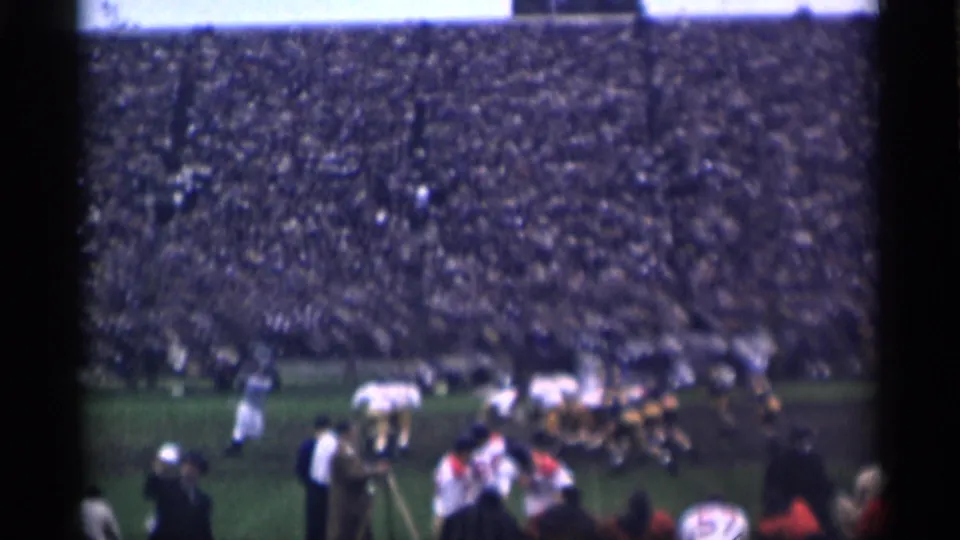A football formation in a crowded San Francisco stadium, captured in blue-tinted 8mm home-movie footage from 1944.