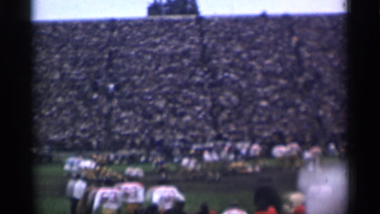 Teams face each other across the field with a dense crowd in the stands.