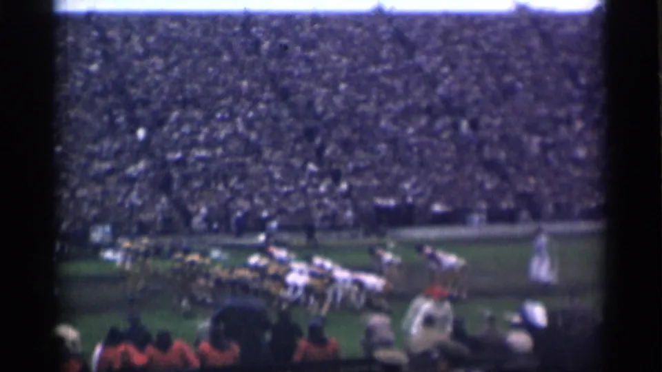 Final 1944 San Francisco football frame with teams near the sideline, spectators in the foreground, and full bleachers behind.