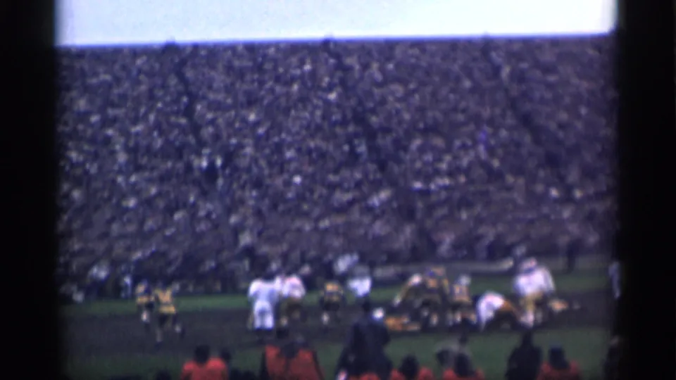 Spectator-shot 8mm frame showing a football play setup at a packed San Francisco stadium in 1944.