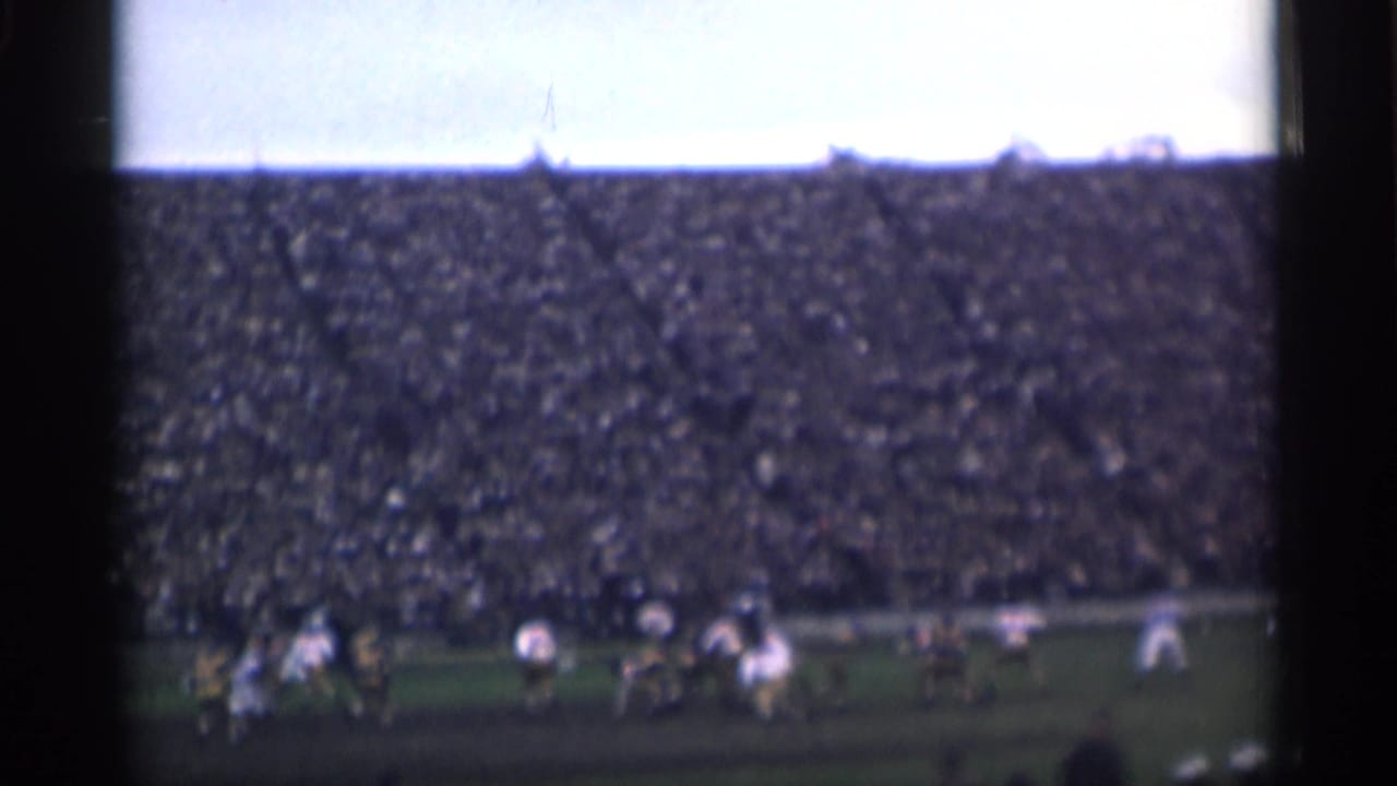 Distant players on a field before packed stadium stands.