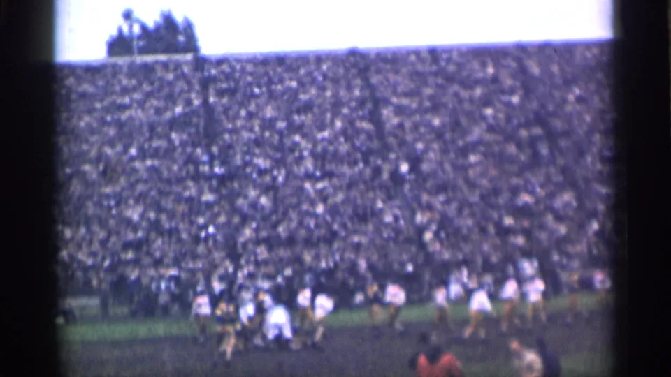 Wide 1944 San Francisco home-movie frame showing players on the field and a large crowd filling the stadium stands.