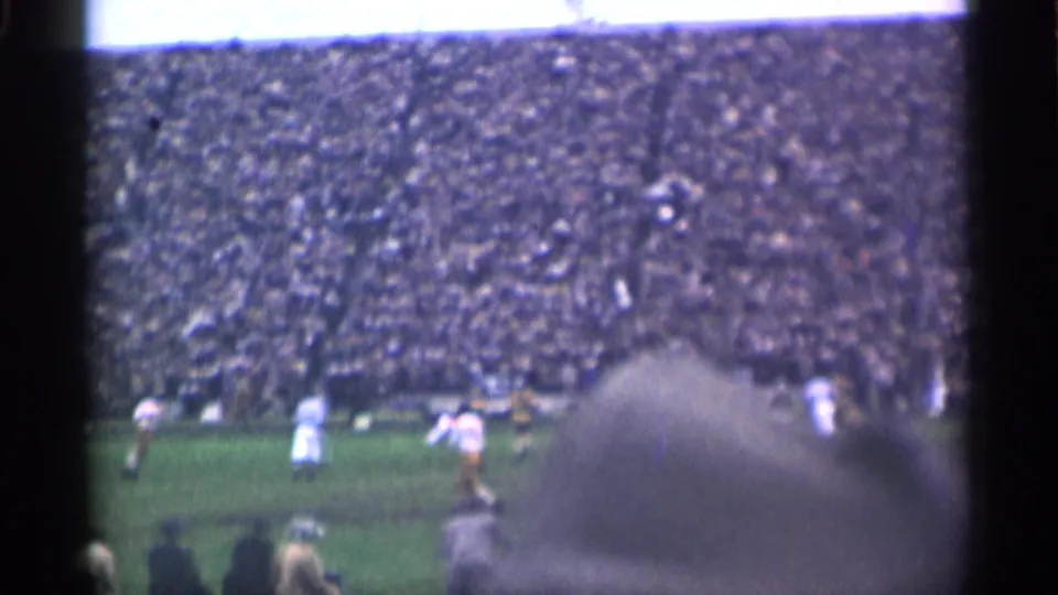 Players in light and dark uniforms are spread across a muddy football field before a large 1944 San Francisco stadium crowd.
