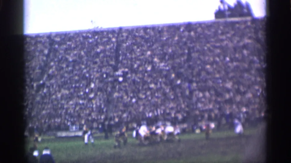 Home-movie footage shows a field-sport play forming in a crowded San Francisco stadium, viewed from a spectator position.