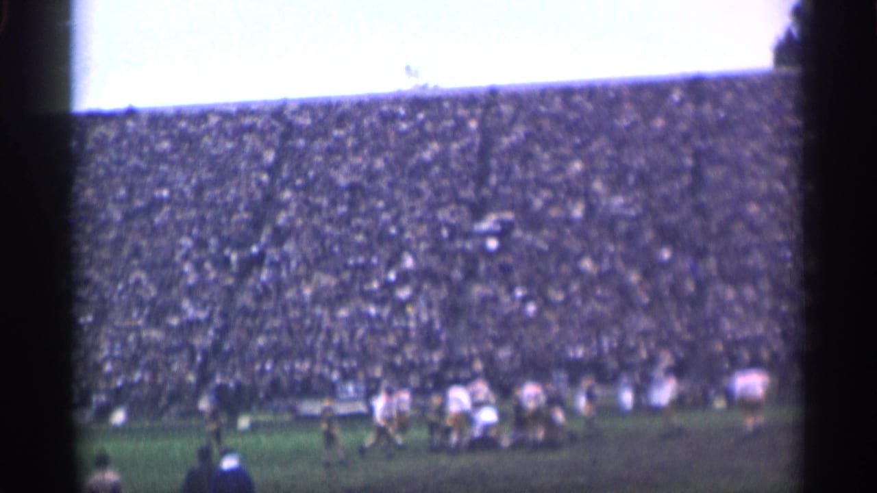 San Francisco 1944 football scene with players in light and dark uniforms moving before a crowded stadium.