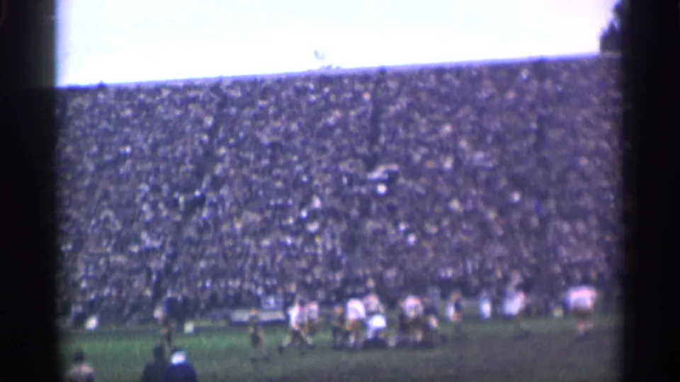 San Francisco 1944 football scene with players in light and dark uniforms moving before a crowded stadium.