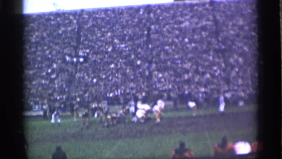 1944 San Francisco stadium view with football players in motion and a large crowd behind the field.