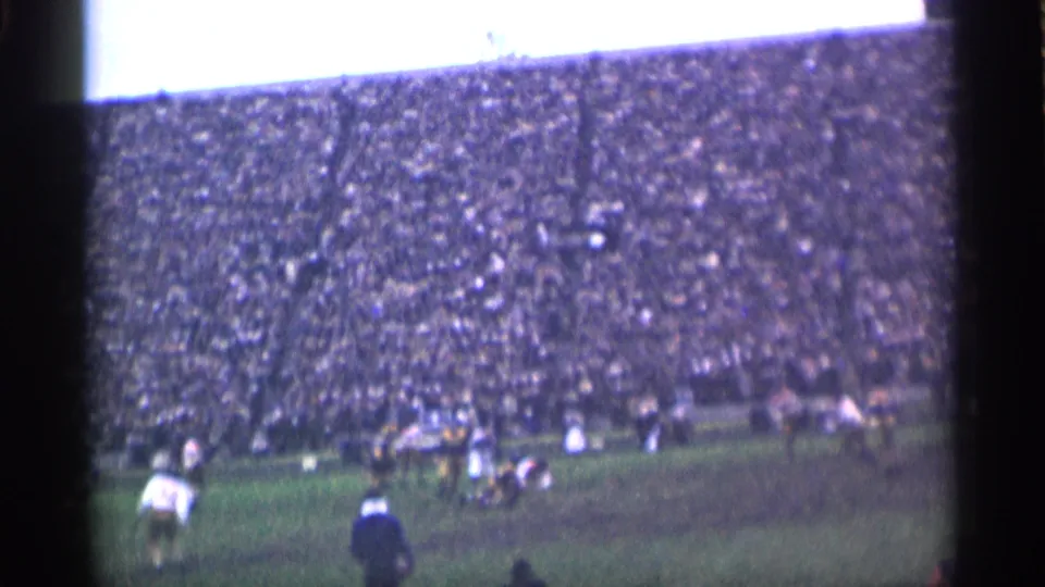 San Francisco 1944 home-movie frame showing football players on the field with a dense stadium crowd in the background.