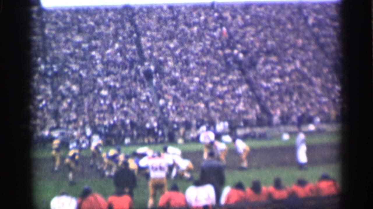 1944 San Francisco football game frame with players running during a play and spectators packed across the stadium seating.
