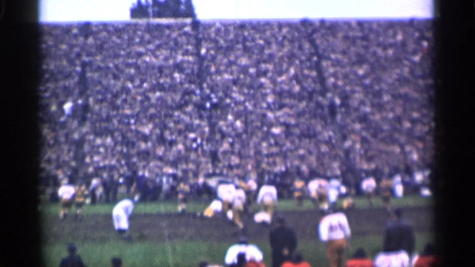 Wide 1944 San Francisco football scene with players in white and dark uniforms spread across the field before crowded stands.