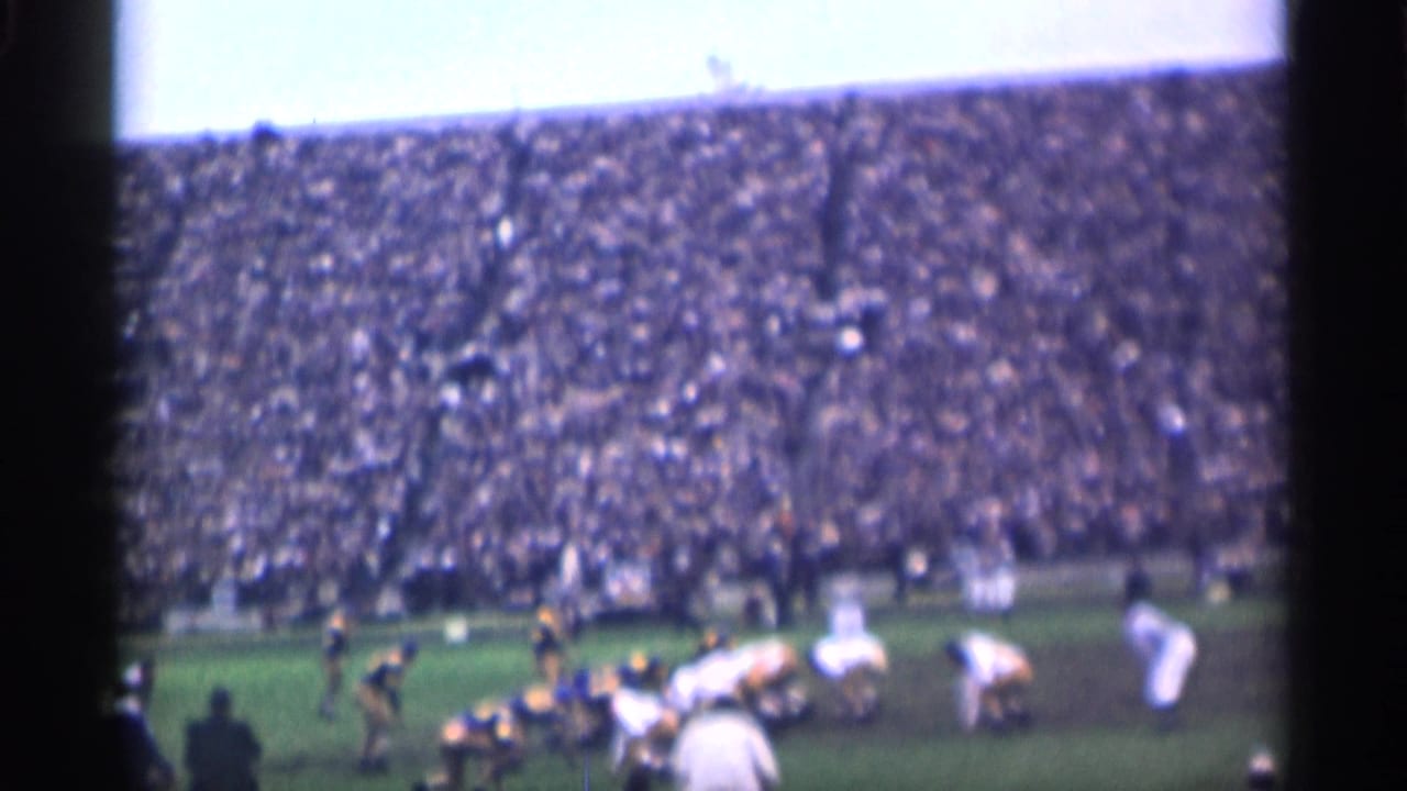 A 1944 San Francisco college football play begins, with players in motion near the line and a packed stadium behind them.