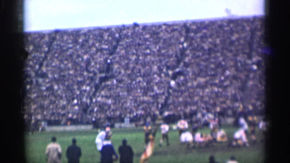 1944 San Francisco football footage shows players near the line of scrimmage with spectators filling the stands behind them.