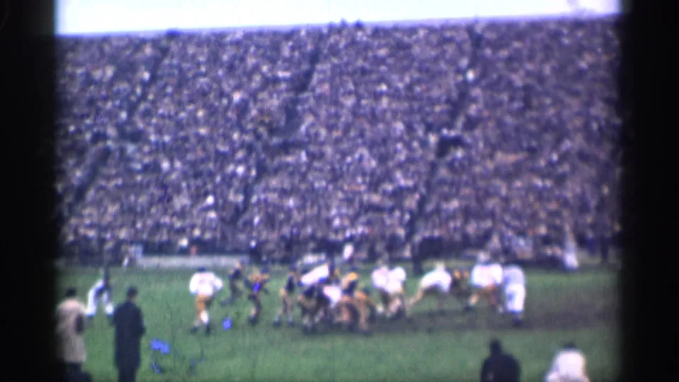 Players converge during a football play on the grass field, framed by a massive San Francisco stadium crowd in 1944 home-movie footage.
