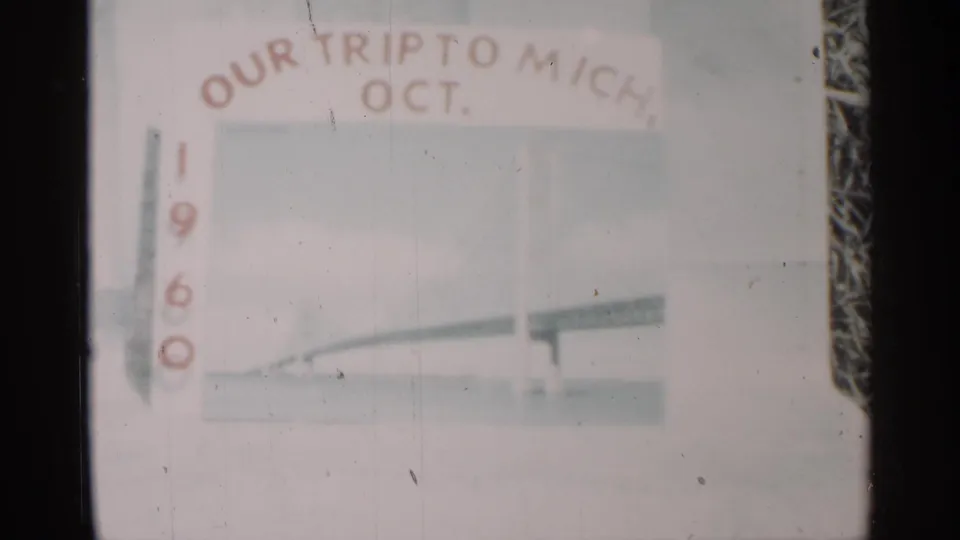Close 8mm view of the 1960 Michigan trip title card, showing arched red lettering, pale blue background, and bridge-like artwork.