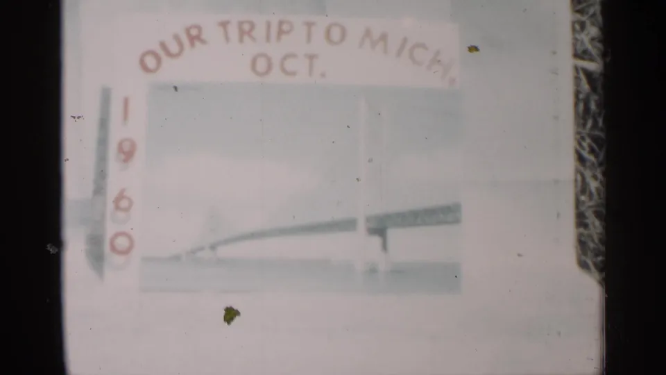 Faded 8mm frame of the October 1960 Michigan trip title card, with vertical date numerals and a simplified bridge illustration.