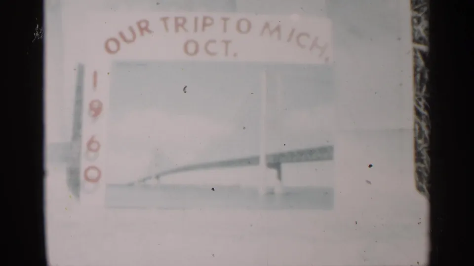 Soft, slightly faded 8mm view of the Michigan trip title card dated October 1960, with red lettering and pale bridge artwork.