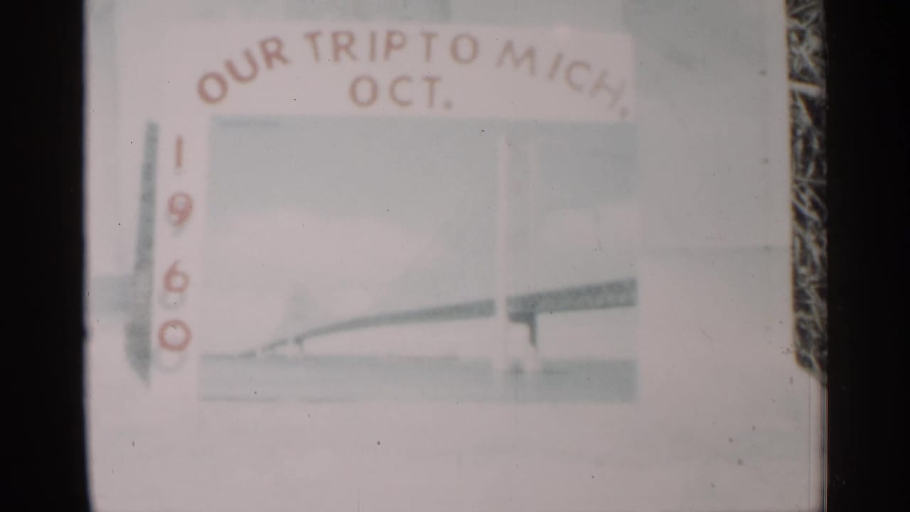 1960 home-movie title card for a Michigan trip, showing pale lettering and a faint travel drawing within the film frame.