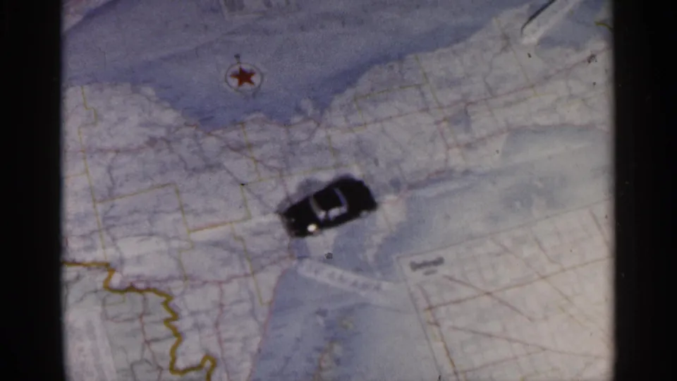 Map route scene with a small car marker, compass symbol, and Great Lakes area visible in faded 1960 8mm footage.