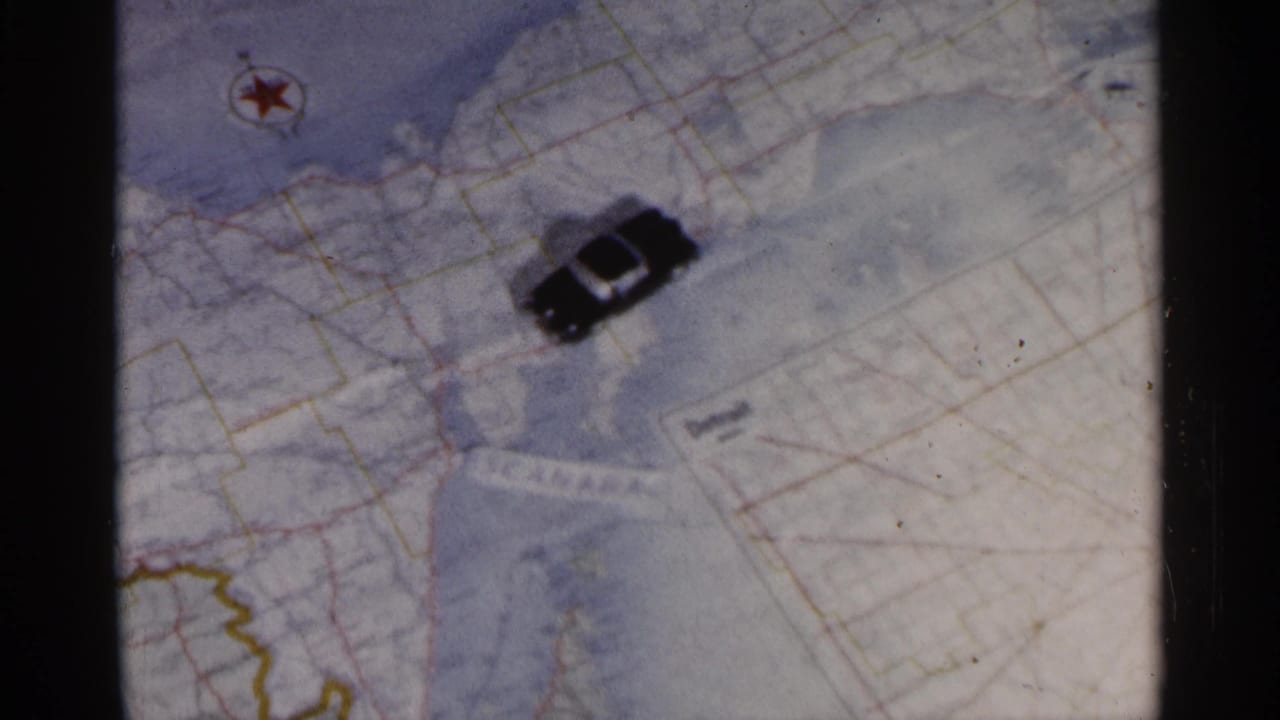 Toy car shifted across a paper map with roads, shoreline, and a red star symbol.