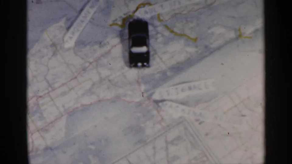 The toy car is now upright in the frame on the Michigan-associated map, suggesting a staged route or play movement.